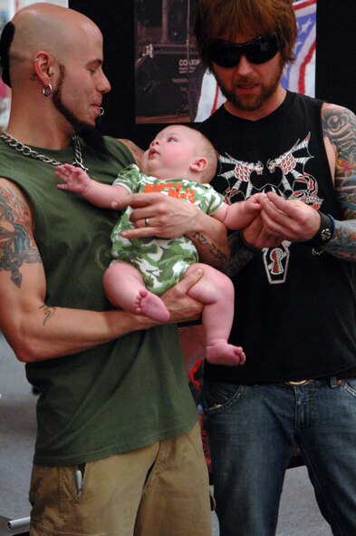 C.J. Pierce and Stevie Benton, members of the band Drowning Pool, hold Shaun Aucion a military dependant, while his mother takes photos during an autograph and photo session held at the Base Exchange, on April 6. The members of the band who have been known for their support of the military with their single "Soldiers" personally requested visiting with Barksdale Airmen. (U.S. Air Force photo by Airman 1st Class Joanna M. Kresge)