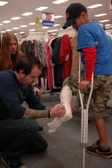 Mike Luce, drummer of the band Drowning Pool, signs the cast of a dependant at the Base Exchange on April 6. The band personally requested to visit Airmen on Barksdale to sign autographs before their show in surrounding Shreveport. (U.S. Air Force photo by Airman 1st Class Joanna M. Kresge)