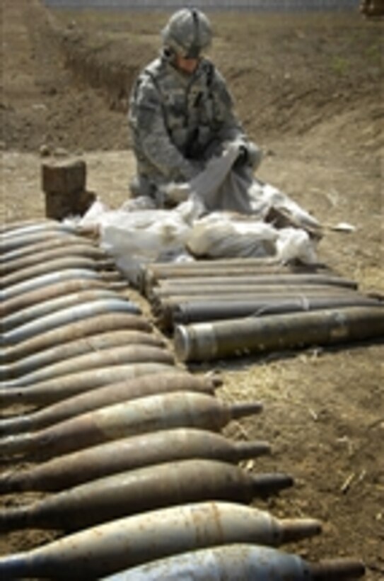 A U.S. Army soldier examines the contents of a bag from a discovered weapons cache outside Abu Thayla, Iraq, on April 13, 2008.  Iraqi National Police and U.S. Army soldiers from 3rd Squadron, 1st Cavalry, 3rd Brigade Combat Team, 3rd Infantry Division discovered and seized 29 120-mm mortar rounds, over 500 mines, seven Chinese 107-mm rockets and five rocket-propelled grenades. The cache will be transported to Forward Operating Base Hammer for disposal by explosive ordnance disposal technicians.  
