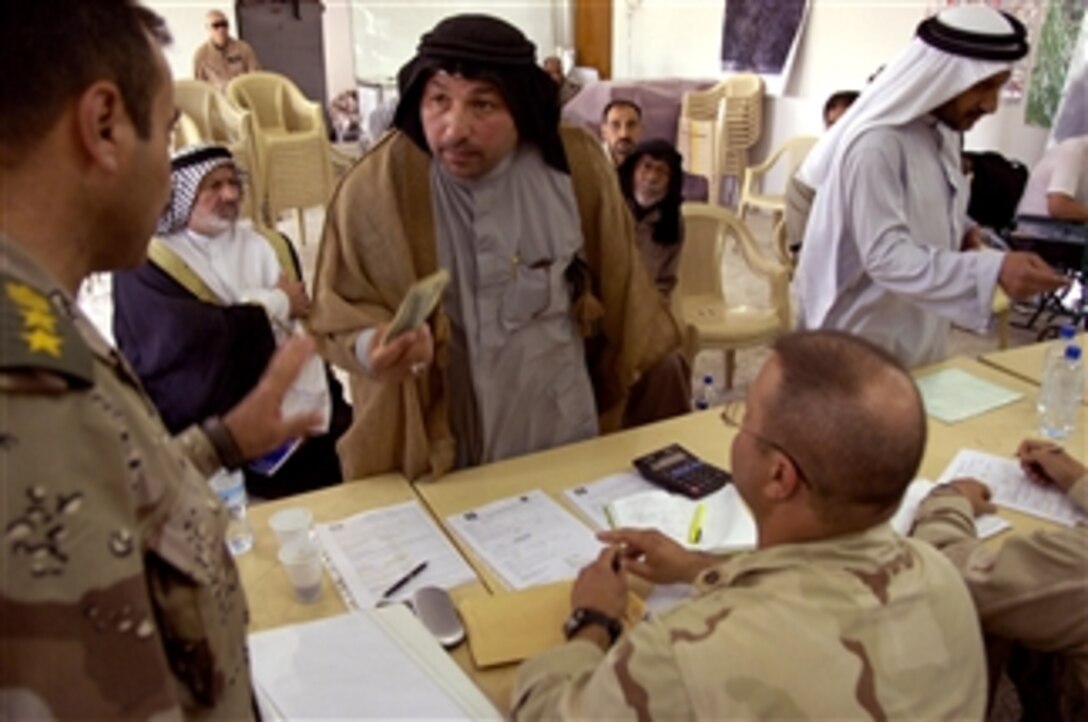 U.S. Navy Cmdr. Dirk Padgett listens as a sheik asks Iraqi army Col. aLaa Aldien a question in the Quibla district of Basra, Iraq, April 14, 2008. The man is one of five sheiks chosen as a superviser to improve his neighborhood's standard of living.
