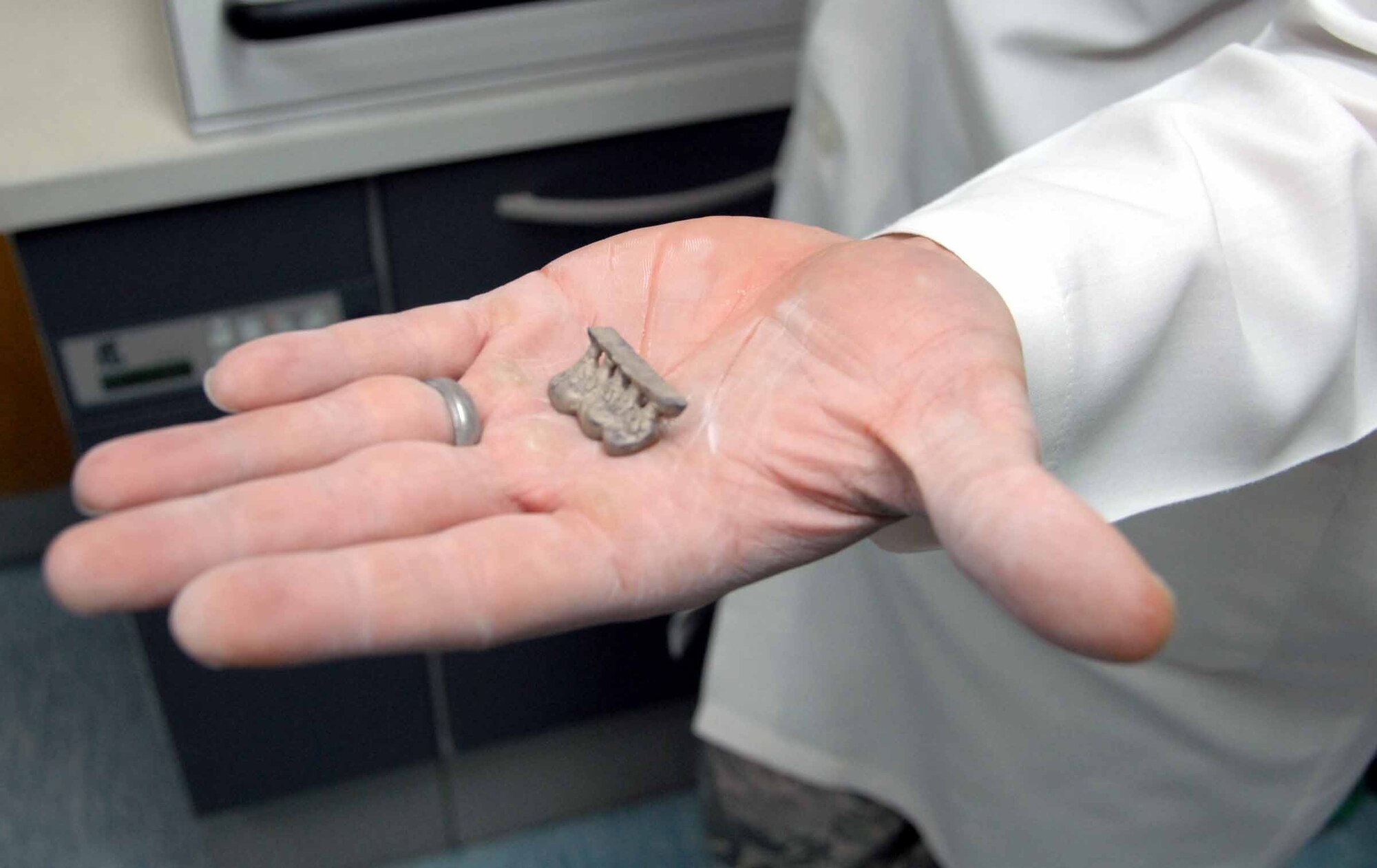 OSAN AIR BASE, Republic of Korea -- Senior Airman Dennis Bermel, 51st Dental Squadron lab technician, shows a gold cast recently removed from a stone molding and sand blasting process April 22. The process is done to remove all stone and oxides, and is part of a two-day gold cast making process. (U.S. Air Force photo/Staff Sgt. Lakisha Croley)
