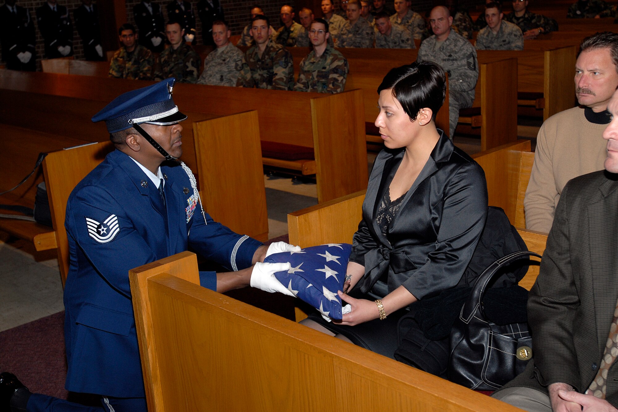 A technical sergeant assigned to the High Frontier Honor Guard presents a folded American flag to a grieving survivor during a mock funeral procession for the Air Force-level LeMay inspection team April 10 at the Peterson chapel. The team inspected the 21st Services Squadron April 7-11 to see if they qualified as the “best of the best” of services squadrons throughout the Air Force. (U.S. Air Force photo/Rob Lingley)