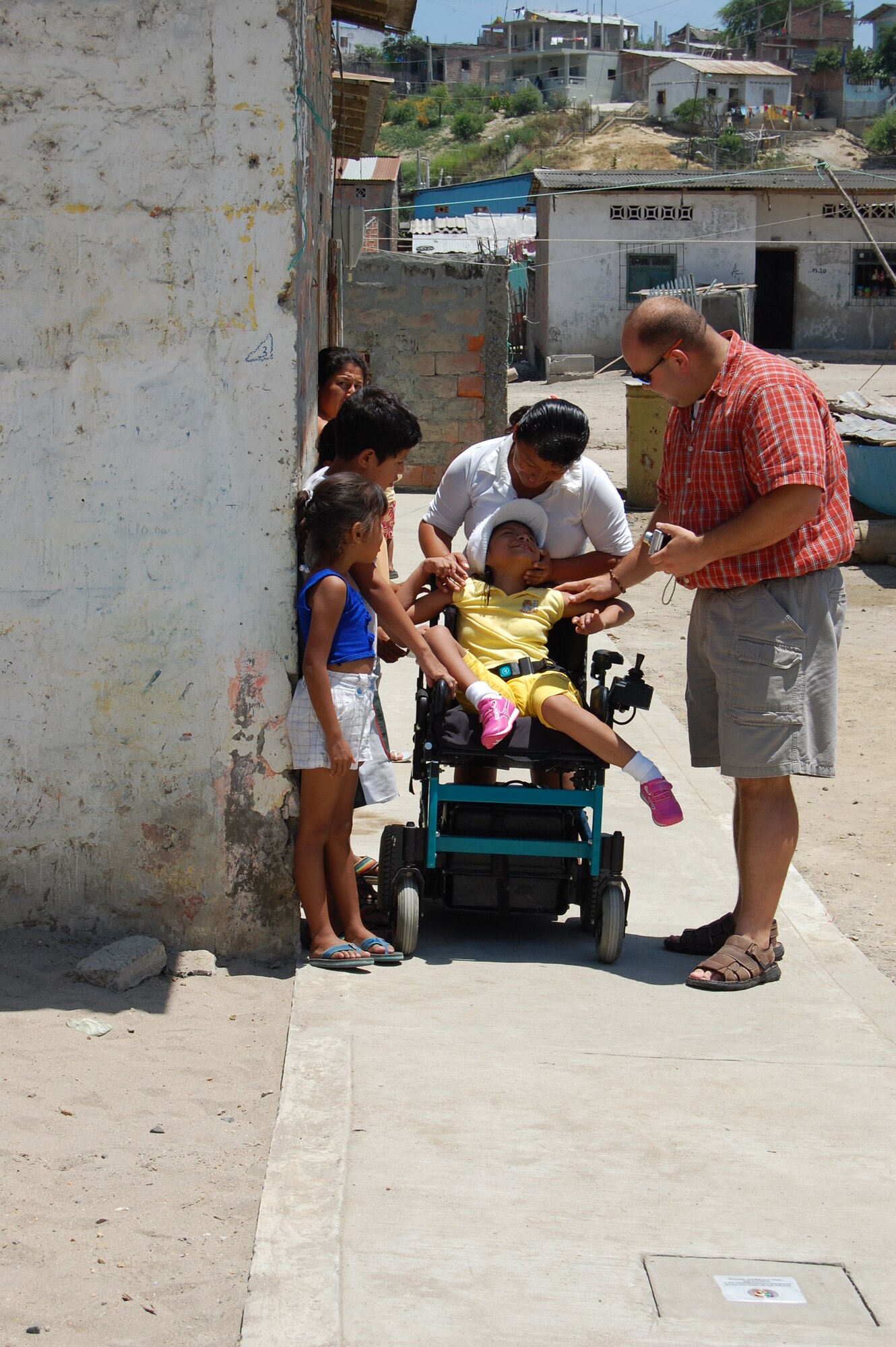 Staff Sergeant Elton Gill, a chaplain’s assistant, talks with 11-year-old Kelly Yuleisy Arcentales and her family during a visit to do the final inspection of a wheelchair ramp that was designed and installed just for her.  The completion of the wheelchair ramp from Kelly’s home to the Jaramijo city sidewalk finalized a three month project by the FOL to provide her with full access to go into her local community.   (U.S. Air Force photo/Capt. Ashley Norris)
