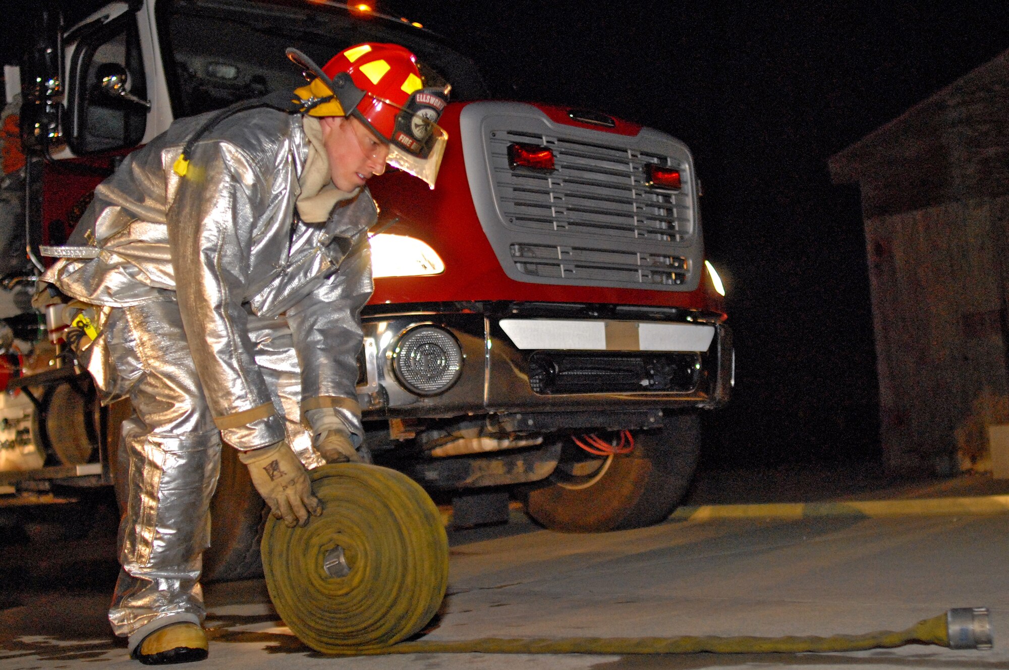 Staff Sgt. Trevor Schubert, 28th Civil Engineer Squadron fire fighter crew chief, rolls a fire hose to return it to storage during a training exercise on Ellsworth April 19. Training burns are conducted regularly to ensure Ellsworth fire fighters maintain readiness and meet Federal Aviation Administration annual training requirements. (U.S. Air Force photo/ Senior Airman Marc Lane)