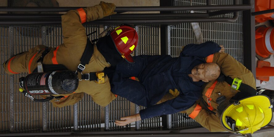 DYESS AIR FORCE BASE, Texas -- Two Airmen fire fighters perform a rescue during a routine structural burn and fire drill exercise April 16. The Airmen were evaluated on speed and efficiency to see what improvements they needed work on. To make things more interesting the fire fighters were tested outside their normal roles, for example one Airman was chosen as the commanding officer for the exercise.  (U.S. Air Force photo by Staff Sergeant Connor W. Estes)  
