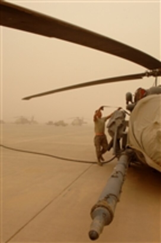 U.S. Air Force Airman 1st Class Jason Schwenn, a crew chief with the 64th Expeditionary Helicopter Maintenance Unit, straps a tarp to an HH-60G Pave Hawk helicopter during a dust storm at Balad Air Base, Iraq, on April 17, 2008.  Schwenn is deployed from Moody Air Force Base, Ga.  