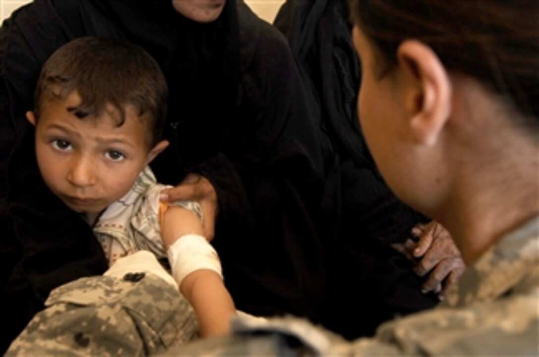 U.S. Army Sgt. Karina Colvin (right), a medic from Charlie Company, 225th Brigade Support Battalion, 2nd Stryker Combat Brigade Team, 25th Infantry Division, treats a young Iraqi boy during a combined medical effort in Bata, Iraq, on March 17, 2008.  