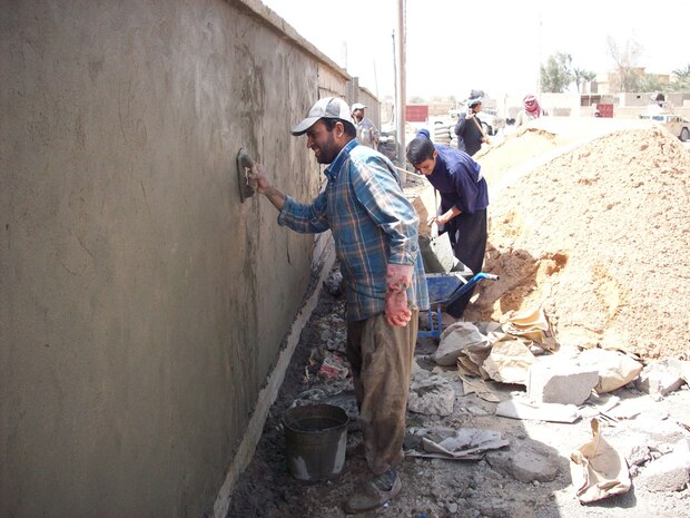Workers, who were hired by a local contractor, put some of the finishing touches on the wall that will surround the newly refurbished teachers institute in Hit, Iraq, April 13. The institute is expected to be completed in June and will be capable of training 300 elementary level teachers at any given time.