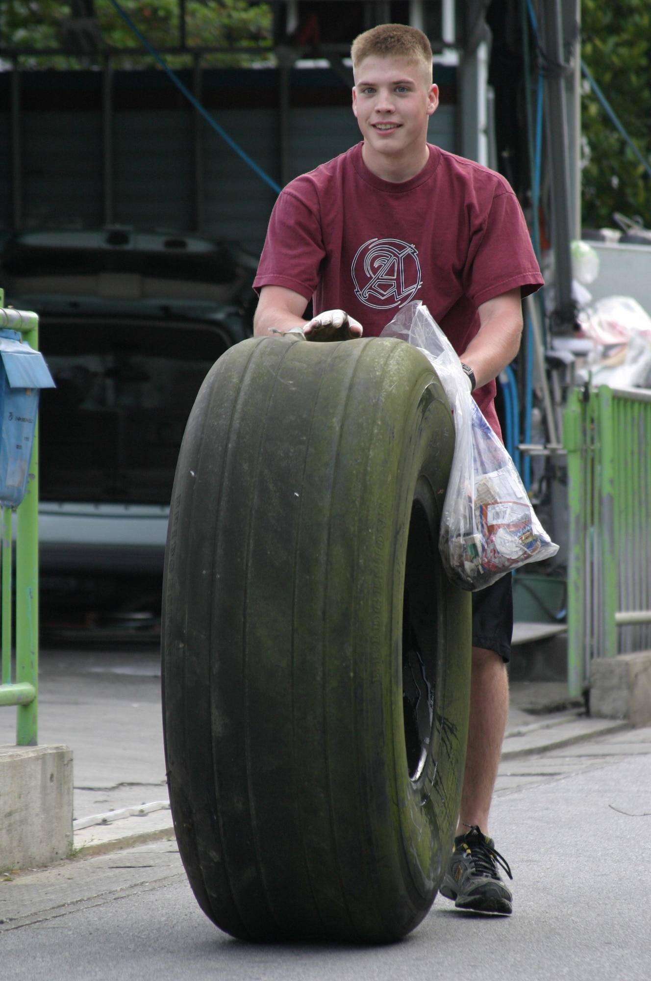 Airman 1st Class Aaron Chamberlain, 18th Component Maintenance Squadron, rolls a piece of trash that would not fit in a trash bag during the Gate 2 Street clean-up sponsored by Airmen Committed to Excellence April 20. More than 145 Airmen, Soldiers, Sailors and family members volunteered to help clean up the area during the event.
 (U.S. Air Force photo/Senior Airman Nestor Cruz) 
