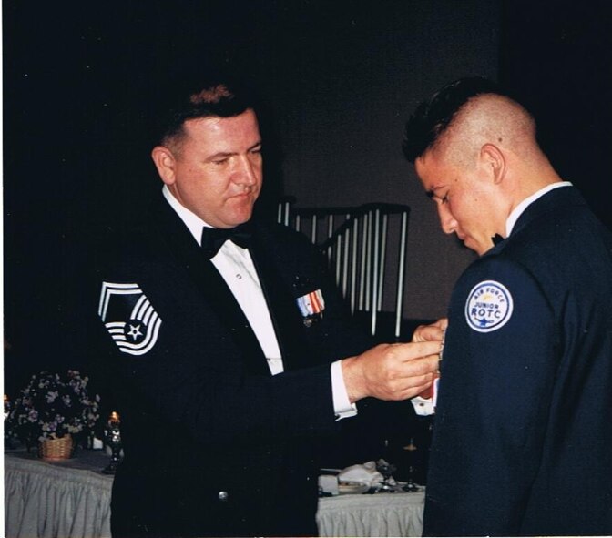 OSAN AIR BASE, Republic of Korea --  Then Senior Master Sgt. Owen Powell, pins on an award for his son Jon Powell, at a Junior Reserve Officers' Training Corps banquet in 1999. The chief's son ended up enlisting in the Air Force in 2001 eventually being stationed with his father at Kunsan Air Base. (Courtesy photo)  