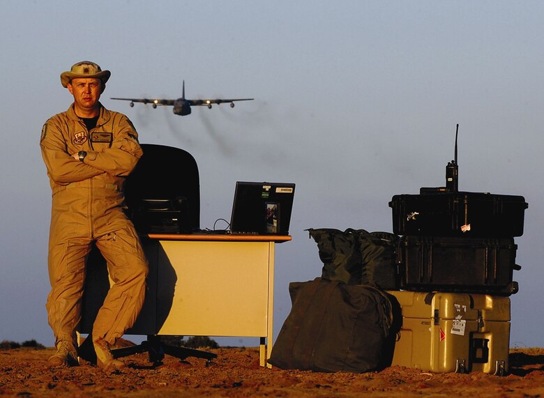 Maj. Jeff Ausborn, 43rd Airlift Wing, stands by his makeshift “desk” on the ground at Camp Lemonier, Dijbouti, while a C-130 flies overhead. Major Ausborn in the air component coordination element at the camp, synchronizing airpower needs for a joint task force in Africa. (U.S. Air Force Photo)