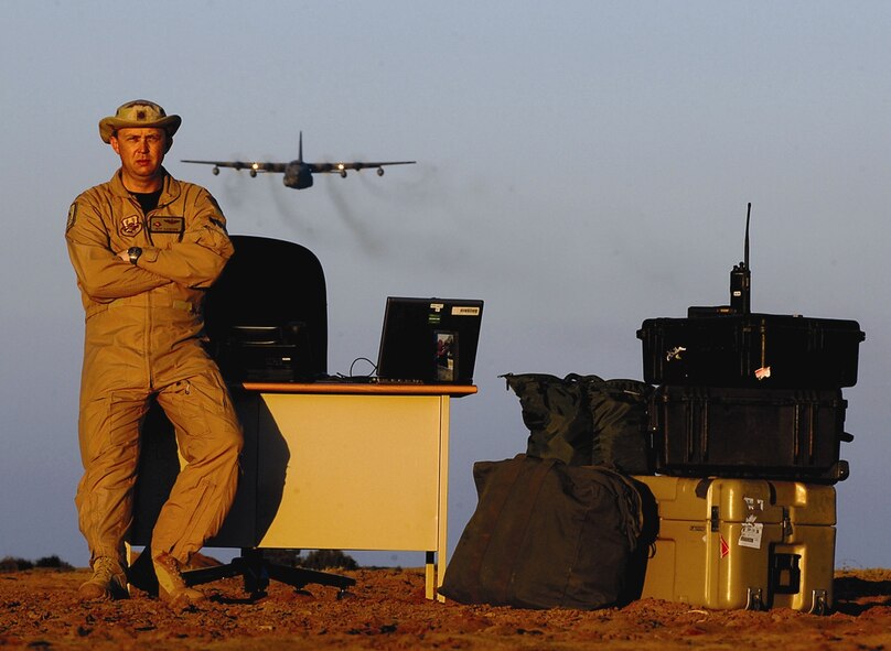 Maj. Jeff Ausborn, 43rd Airlift Wing, stands by his makeshift “desk” on the ground at Camp Lemonier, Dijbouti, while a C-130 flies overhead. Major Ausborn in the air component coordination element at the camp, synchronizing airpower needs for a joint task force in Africa. (U.S. Air Force Photo)