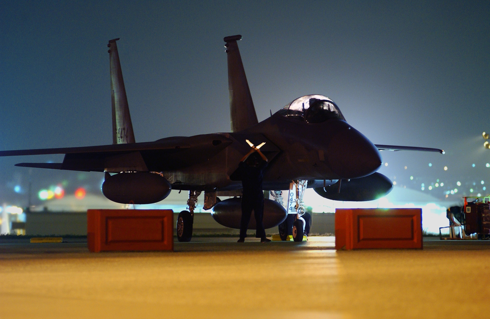 A Kadena Air Base crew chief prepares to marshal out an F-15C Eagle during the early morning hours at Kadena Air Base, Japan, April 23 before its departure to the U.S., symbolizing the end of the Iron Flow program here. The aircraft was one of three jets that left to be transferred to Air National Guard units under Iron Flow which exchanged Kadena's older F-15's with newer models from other active- duty bases. All newer jets have been received and these were the last three older aircraft to be turned in. (U.S. Air Force photo/Senior Airman Jeremy McGuffin) 
