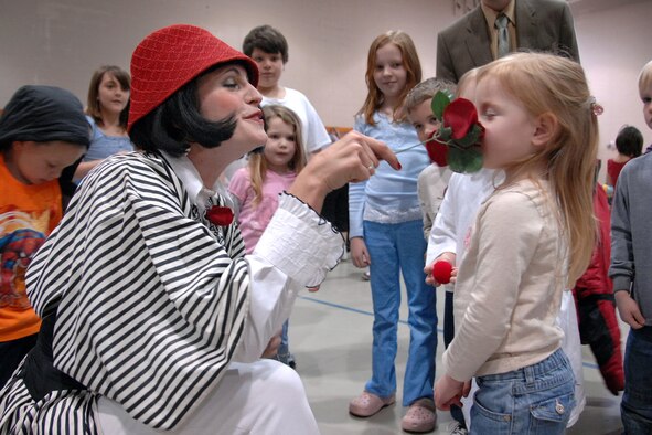 Pearl, a mime from the Cirque de Soleil’s Saltimbanco touring troupe, lets Kaydence Erickson, 3, smell a rose after giving her a clown nose during their performance April 1 at the Offutt Youth Center. The performance featured stilt walkers and mimes. The Cirque du Soleil’s touring troupe came to Offutt as part of a special ‘Month of the Military Child’ event during their regular promotional stops for their show in Omaha. (U.S. Air Force Photo/Josh Plueger)