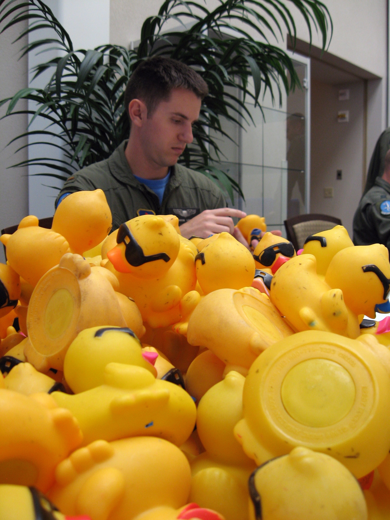 Second Lt. Brandon Liabenow works though a pile of rubber ducks April 18 that are set to race in the 2nd Annual Children's Miracle Network Rubber Duck Rivery Derby in May. Lieutenant Liabenow and other 80th Operations Support Squadron personnel and family members and CMN representatives placed numbers on about 10,000 rubber ducks in preparation of the race. (U.S. Air Force photo/Mike McKito)