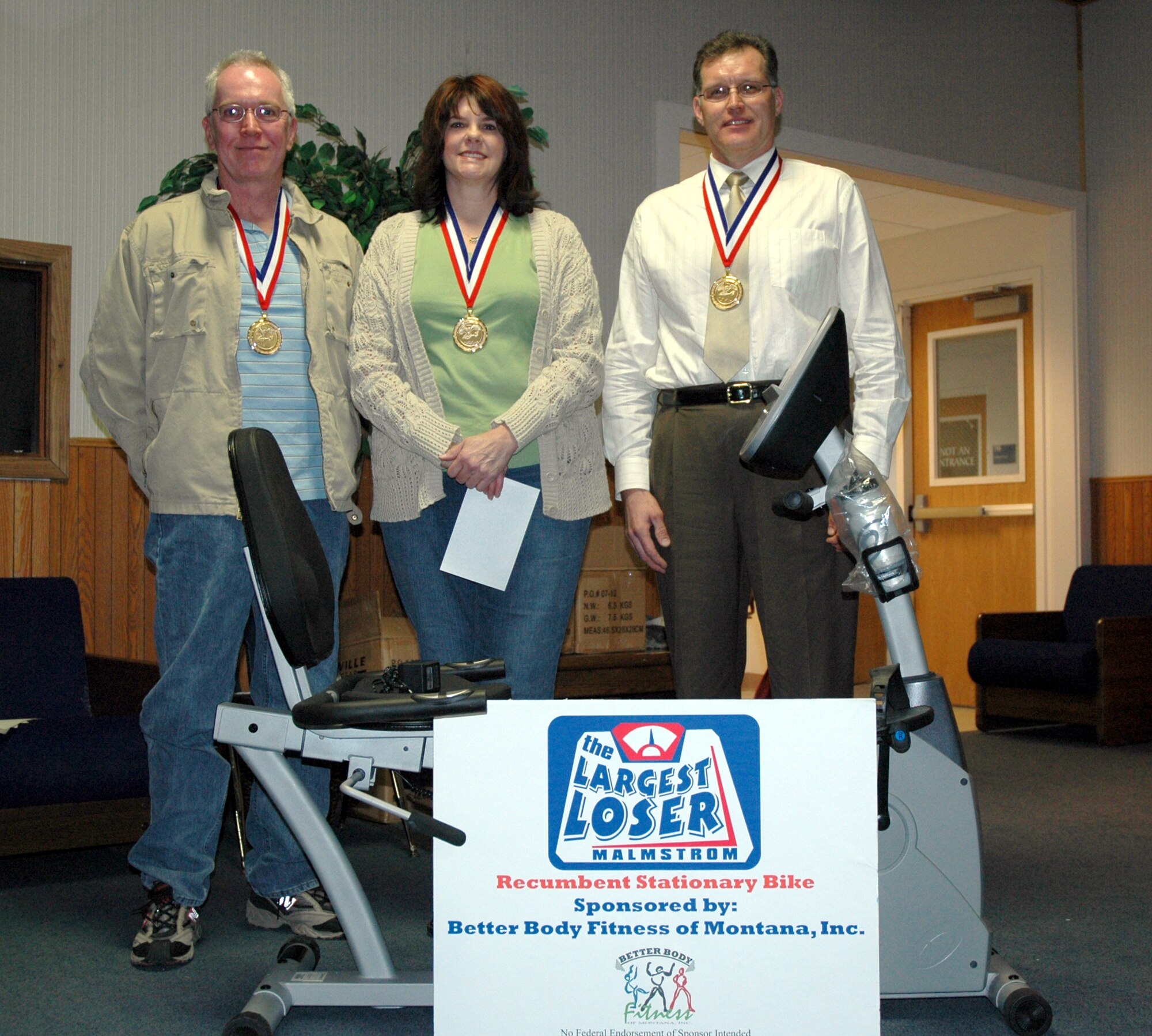 (Left to right) Roger Barnes, Pam Barnes and Jerry Kain were awarded the Largest Loser prizes for their accomplishments during season three of the program which kicked off January 14. Mr. Barnes lost five inches off his abdominal circumference, Mrs. Barnes  lost the greatest percentag of body fat at 7.6 percent, and Mr. Kain lost the most total weight at 31.50 pounds. He was also the winner of the recumbent bicycle, pictured here. (U.S. AIr Force photo/Valerie Mullett)