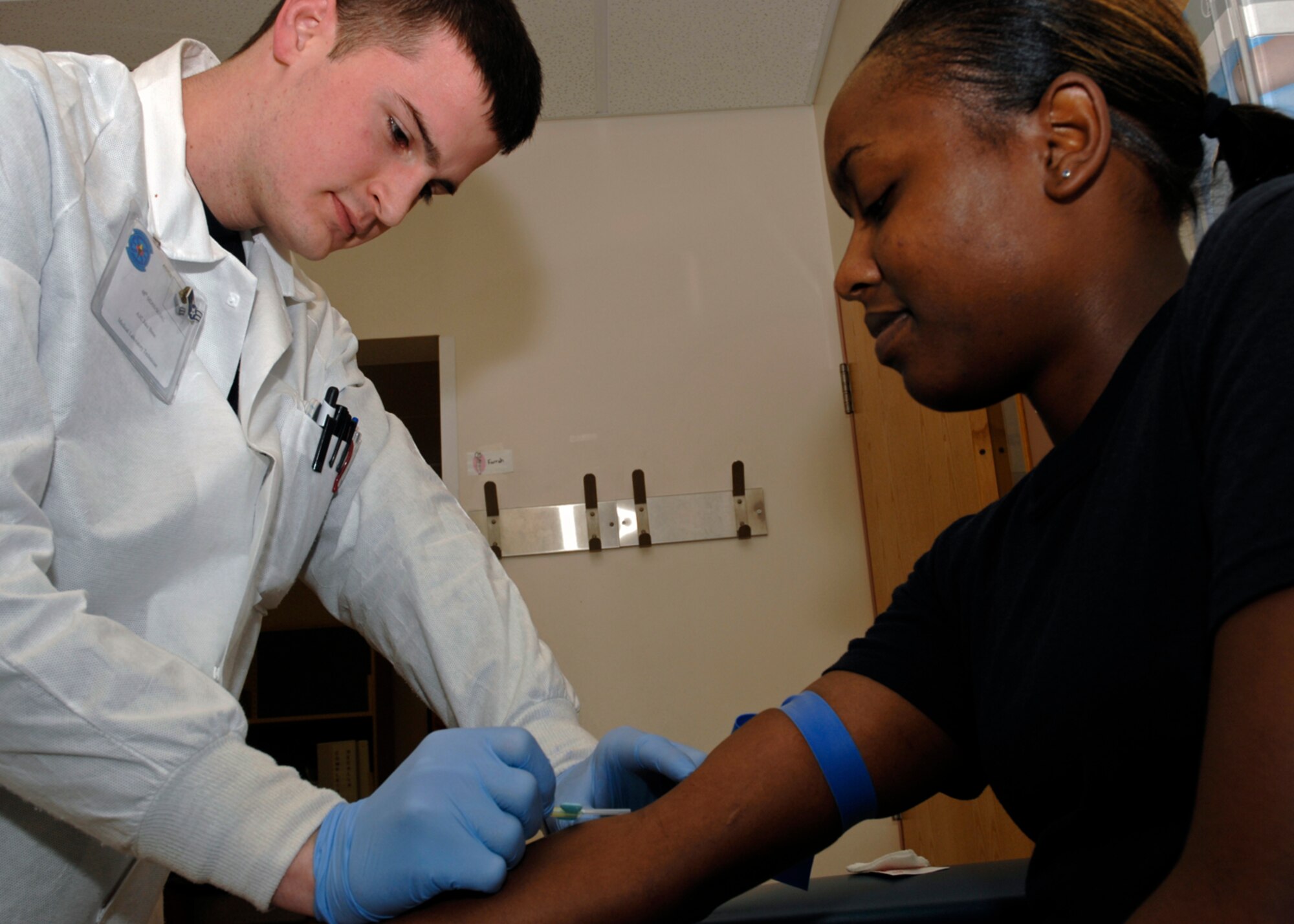 Airman 1st Class Jake Bunn, laboratory technician, demonstrates how to draw blood from Airman 1st Class Milika Njenga, 48th Medical Support Squadron April 2 at RAF Lakenheath, England. More than150 beneficiaries have their blood drawn every day at the pathology lab. (U.S. Air Force photo by Airman Perry Aston)