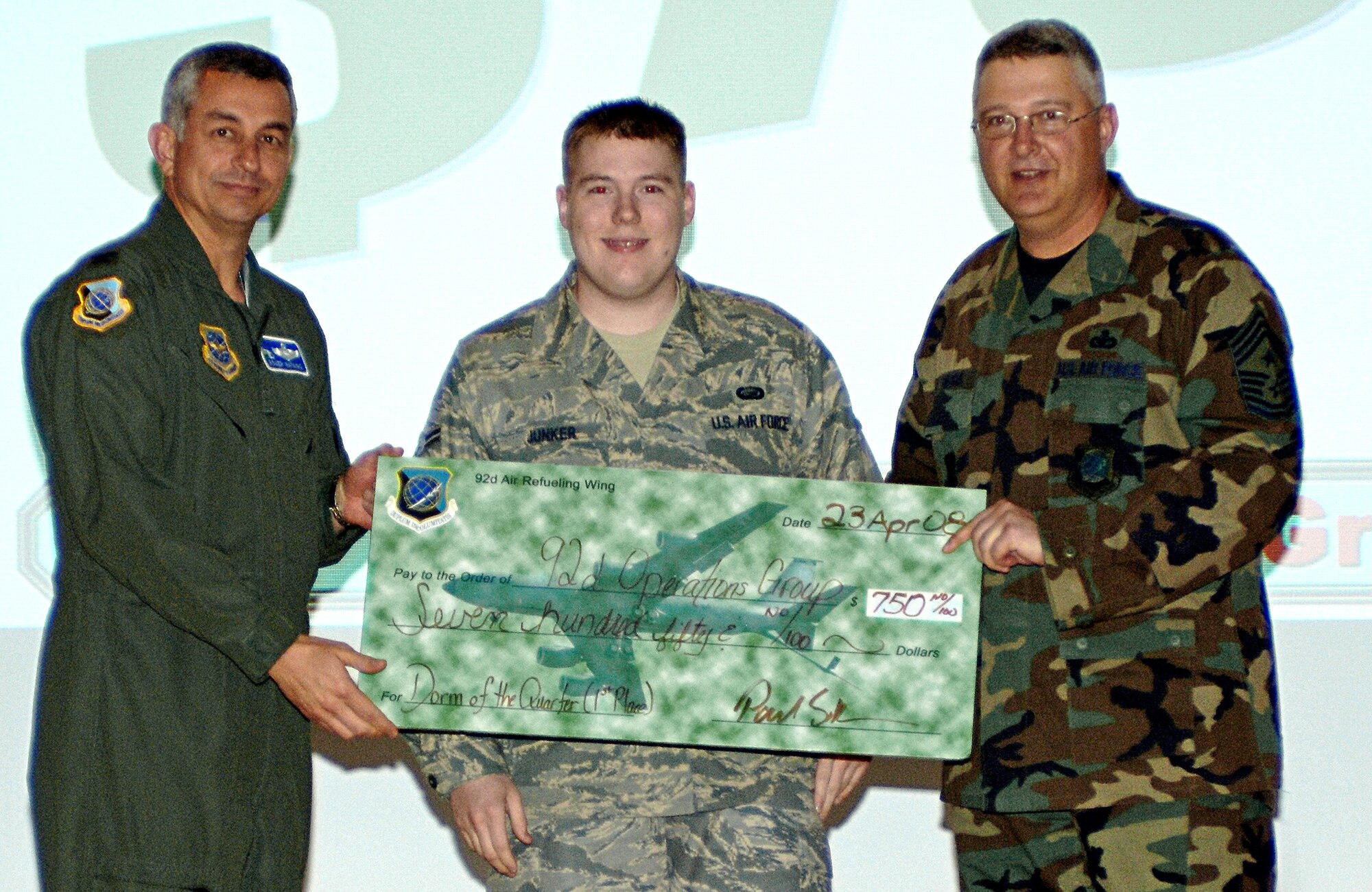 FAIRCHILD AIR FORCE BASE, Wash. – Col. Roger Watkins, 92nd Air Refueling Wing acting commander, and 92nd ARW Command Chief Master Sgt. Paul Sikora, present the Dorm of the Quarter award to Airman 1st Class Adam Junker, 92nd Operations Group dormitory resident, at the base theater April 22. The award is given to dorm residents who display “above and beyond” responsible behavior. (U.S. Air Force photo / Airman 1st Class Melissa Barnett)