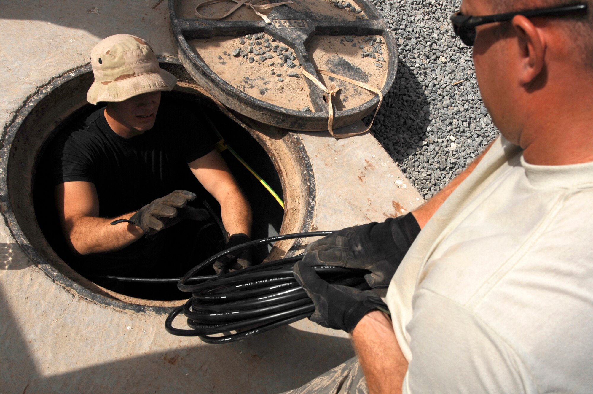 Airman 1st Class Theodore Nichols, left, grabs a bundle of fiber-optic cable from Staff Sgt. Christopher Billings at an air base in Southwest Asia.  Airman Nichols is deployed from the 96th Communications Squadron, Eglin Air Force Base, Fla.  Sergeant Billings is deployed from the 85th Engineering Installation Squadron at Keesler.  They’re assigned to the 386th Expeditionary Communications Squadron.  (U.S. Air Force photo by Staff Sgt. Patrick Dixon)