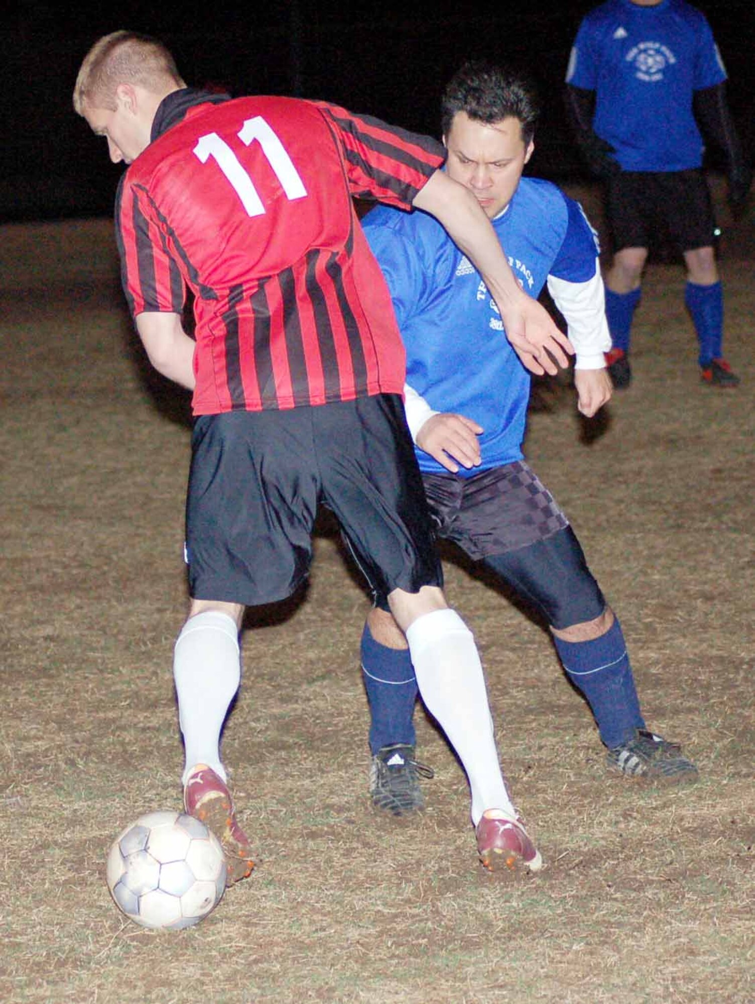 Dave Acklin (11), 31st Combat Communications Squadron forward, attempts to dribble the ball past 38th Engineering Installation Group defender Cory Bruce during the first half of game at the Tinker Sports Complex on April 17.  (Air Force photo by John E. Banks)
