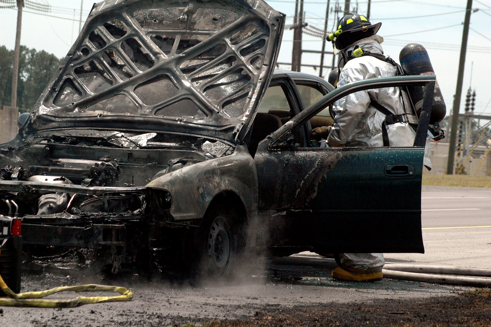 EGLIN AIR FORCE BASE, Fla. -- A fireman from the 96th Civil Engineer Squadron Fire Department finishes hosing down a vehicle which caught on fire on Eglin Parkway April 24. Members from the fire department and the 96th Security Forces Squadron immediately responded to the scene where traffic was cordoned off as crews worked to control the fire. (U.S. Air Force photo/Airman 1st Class Anthony Jennings)