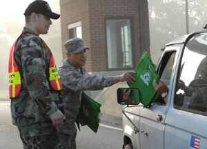 LANGLEY AIR FORCE BASE, Va. -- Tech. Sgt. Allan Araneta (left), 1st Logistics Readiness Squadron, hands out reusable grocery bags at the West Gate April 24 to show the Langley’s support of carpooling during earth week while Senior Airman Justin Cyr, a 1st Security Forces augmentee from the 30th Intelligence Squadron, checks identification. (U.S. Air Force photo/Senior Airman Christopher L. Ingersoll)