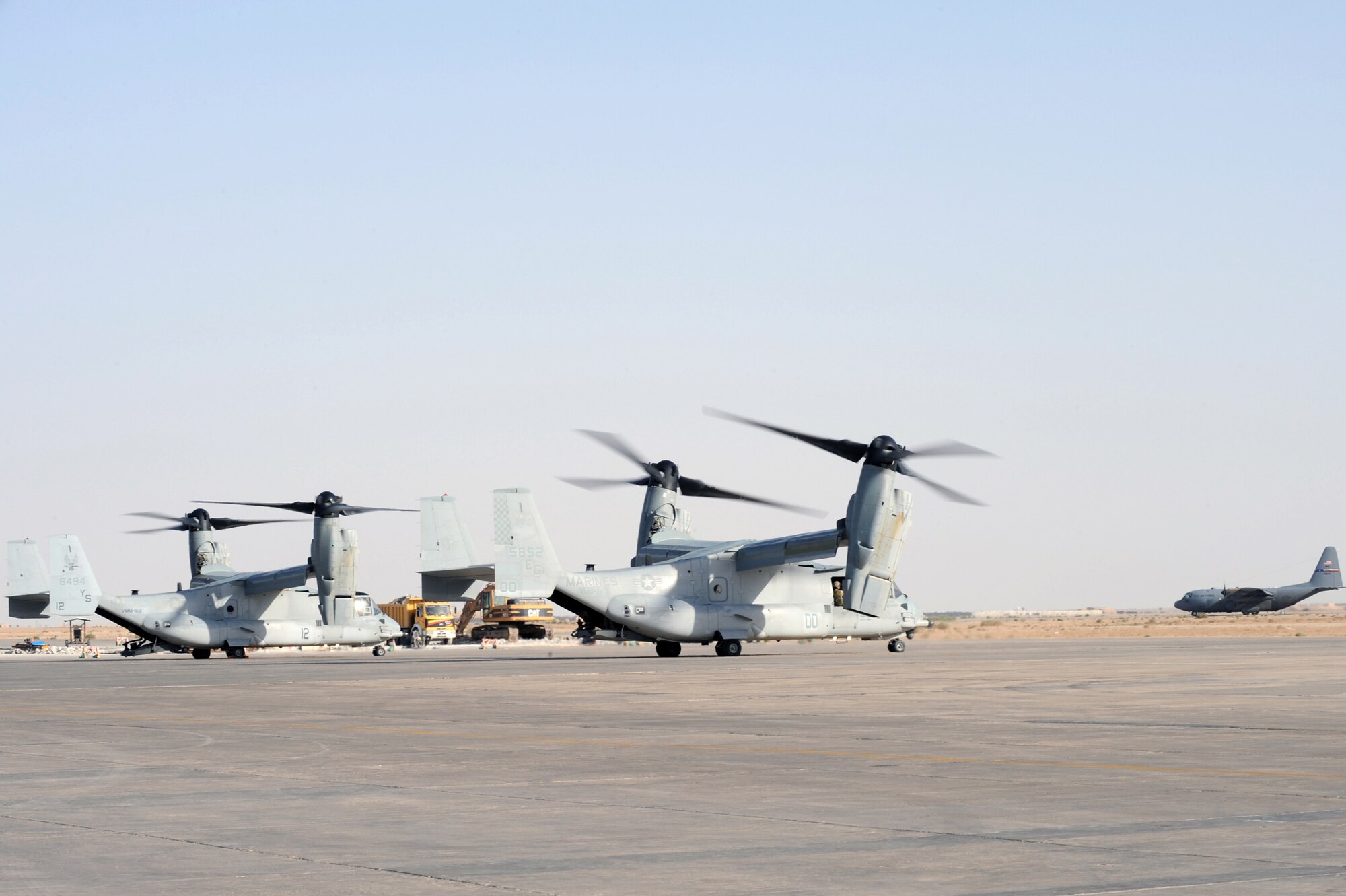 ALI BASE, Iraq -- V-22 Osprey's wait for takeoff as a C-130 arrives here April 24.  The V-22 Osprey is an aircraft used to transport Airmen, Troops, and cargo.  (U. S. Air Force photo / Tech. Sgt. Sabrina Johnson)  