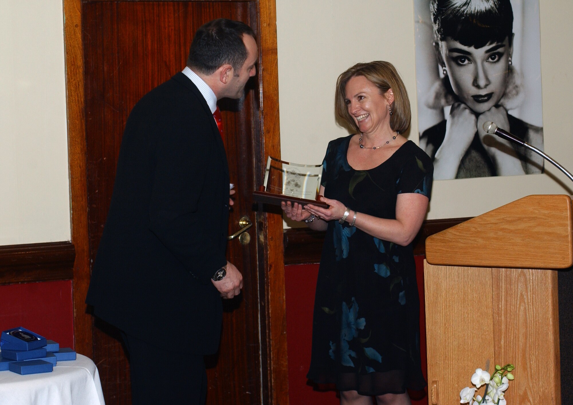 Collin Wills, 48th Fighter Wing honorary commander presents Gisele Novak, Officer and Civilian Spouses Club representative with the British-American Committee American Award during the "Rock the Red Carpet" dinner April 18 at the Eagle's Landing, RAF Lakenheath, England. The dinner was a combination of the OCSC’s annual British-American social and the BAC's community award ceremony.