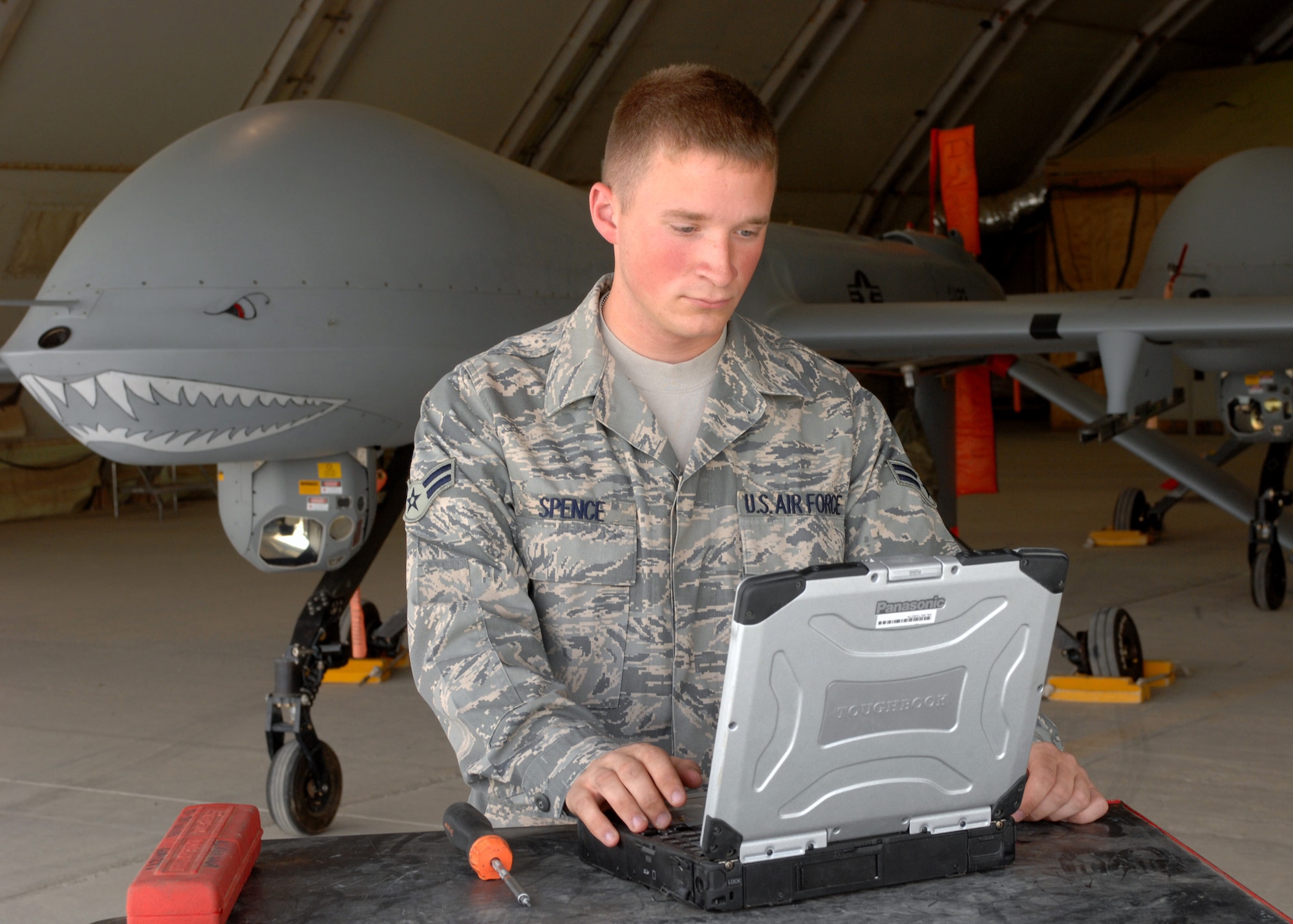 BAGRAM AIR FIELD, Afghanistan - Airman 1st Class Troy Spence, 62nd Expeditionary Reconnaissance Squadron crew chief, looks over technical orders on his laptop while performing maintenance on a MQ-1 Predator in Afghanistan. The unit’s primary role is to launch and recover Predators supporting Operation Enduring Freedom. Airman Spence is deployed from the 432nd Aircraft Maintenance Squadron, Creech Air Force Base, Nev. (U.S. Air Force photo by Master Sgt. Demetrius Lester)