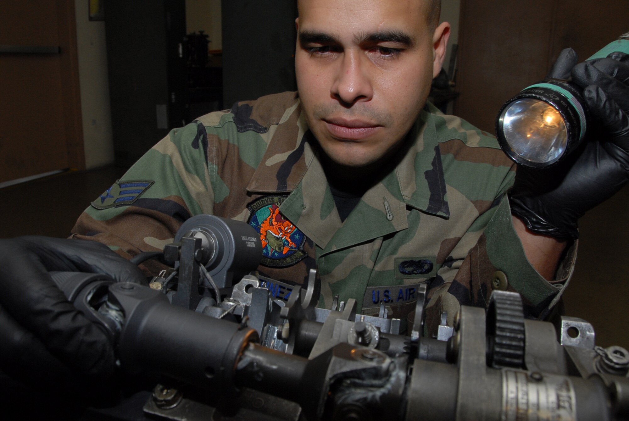 Senior Airman Sergio Martinez, 18th Equipment Maintenance Squadron, uses a flashlight to inspect a M61-AI 20 Millimeter automatic gun at Kadena Air Base, Japan, March 5, 2008. This inspection ensures that the automatic gun is assembled correctly. (U.S. photo/Staff Sgt. Darnell T. Cannady)