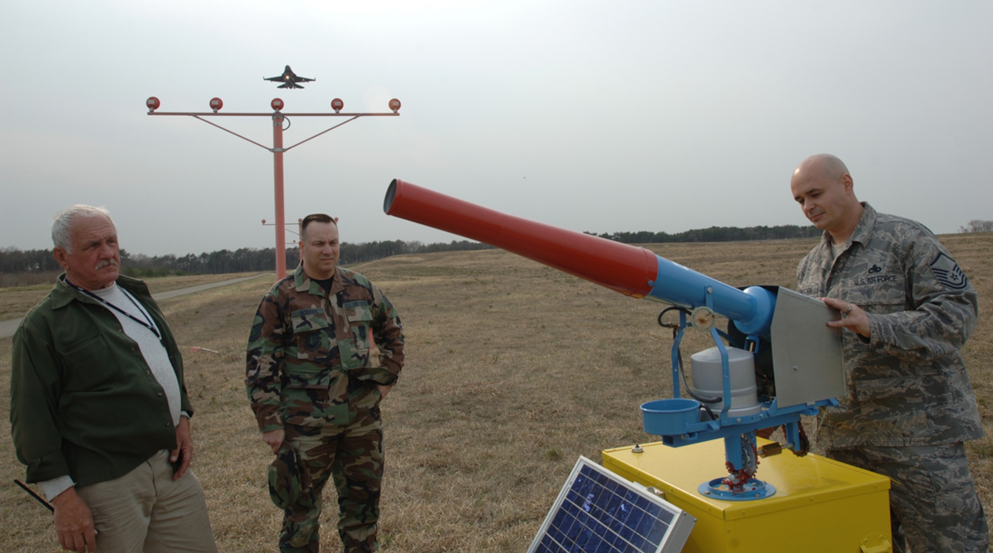MISAWA AIR BASE, Japan -- Marty Schoenheiter, customs communications expert, and Tech. Sgt. Russell McBride, 35th Fighter Wing Public Affairs, watch Master Sgt. John Cernucan, noncommissioned officer in charge of flight safety, inspect a bird cannon on the flightline April 23, 2008.  (U.S. Air Force photo by Senior Airman Robert Barnett)