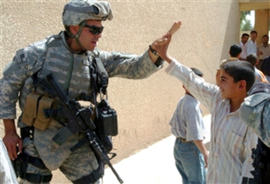 U.S. Army Staff Sgt. Jason Gartsu gets a high-five from a student at Abu Shear school, April 14, 2008, in the Monsouri area of Iraq as he and other soldiers deliver backpacks, soccer balls and notebooks. Gartsu is assigned to the 3rd Infantry Division's 1st Battalion, 76th Field Artillery, 4th Brigade Combat Team.