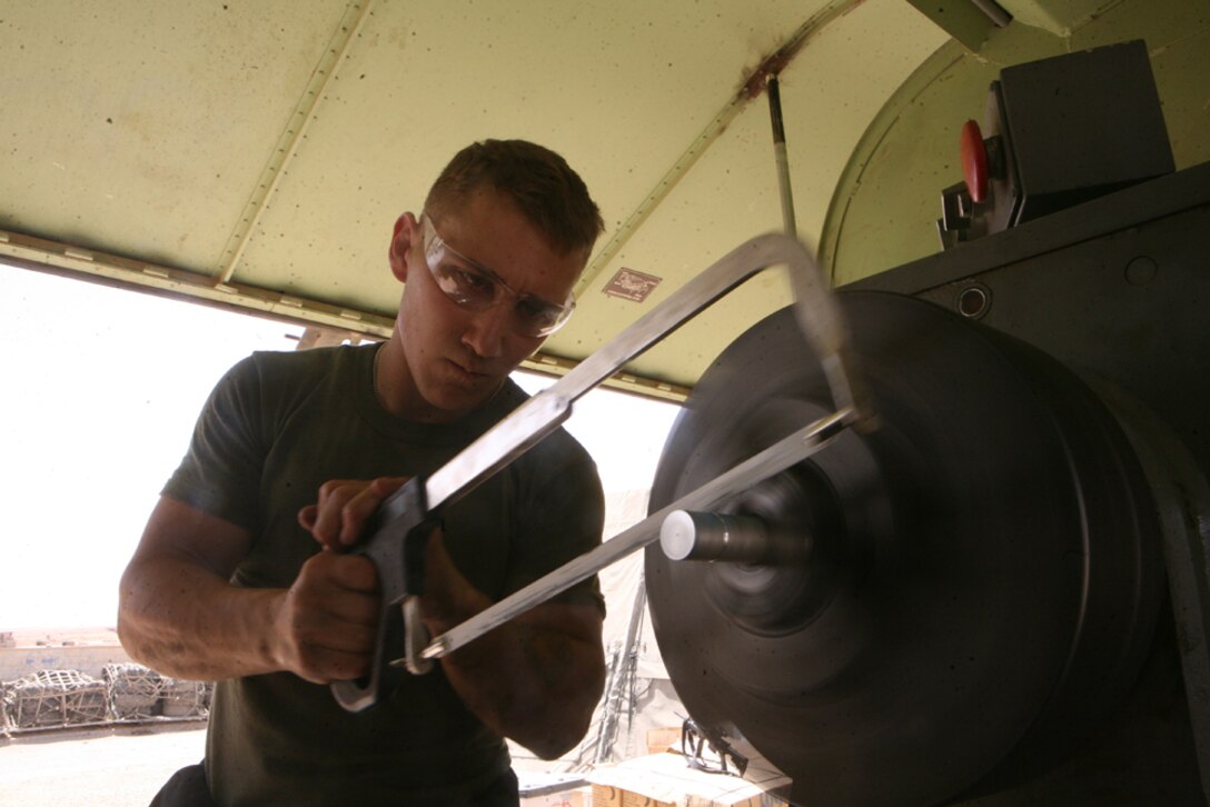 Using a hack-saw to make grooves in a welding hose connector, Cpl. Matt G. Pelkey, a machinist Battalion Maintenance, 2nd Light Armored Reconnaissance Battalion Regimental Combat Team 5, makes a groove on the hose at Camp Korean Village, Iraq, April 25. The machinists work in a trailer containing a large portable machine called the "Tornado," which Gunnery Sgt. John E. Fishcer, platoon sergeant of Battalion Maintenance and machine shop staff noncommissioned officer in charge, describes as resembling a large hot dog stand. They work long hours taking orders at any given time, ensuring Marines and sailors have the parts they need to make repairs or create parts for anything from a vehicle to a weapons system.