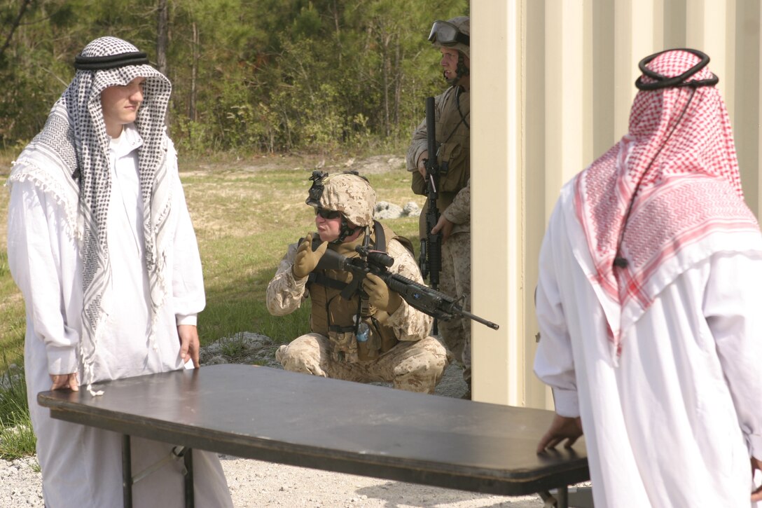 Sgt. Damien Senerchia of 2nd Marine Logistics Group communicates with Marines to the rear while role-players in local garb go about their daily business during the final exercise of the Combat Hunter course. Marines from Combat Logistics Batallion 26 were the first support Marines to take the Combat Hunter course here, which taught them to analyze highly complex environments and act decisively. As the Combat Logistics Element for the 26th Marine Expeditionary Unit, CLB-26 will deploy with the MEU this fall in support of the Global War on Terror.