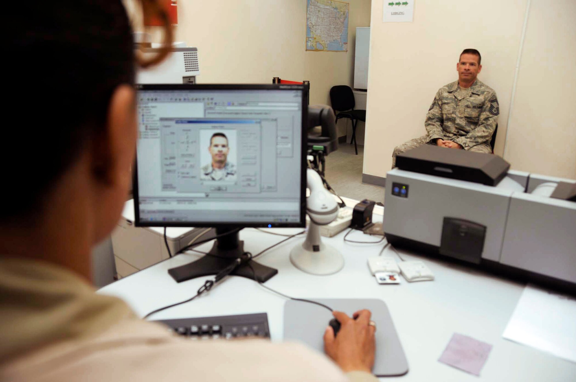 Tech. Sgt. Arvalon Harleston creates a new common access card for Senior Master Sgt. Ruel Gadbury April 23 at an air base in Southwest Asia. This is one of the many personnel services Airmen in the Personnel Support for Contingency Operations, or PERSCO, office provide for deployed troops.  (U.S. Air Force photo/Senior Airman Domonique SImmons)
