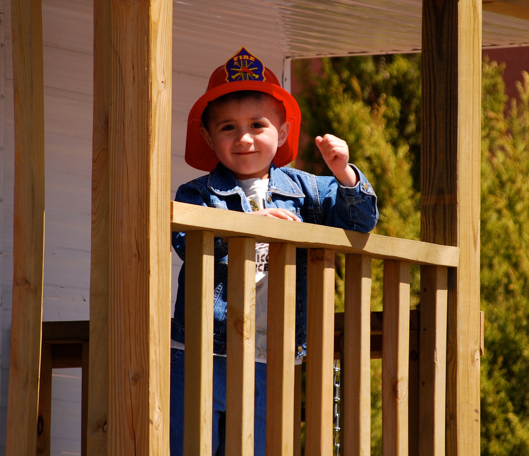 A local child waves from the “deck” of the Peterson Fire Department’s safety trailer April 19. The fire department took the trailer to Colorado Springs’ Earth Day celebration at the city’s famous Garden of the Gods park to teach kids about fire and weather safety. Kids participated in a variety of activities, including “escaping” from a smoky room using a fire escape ladder. (U.S. Air Force photo/Burke Ferrin)  