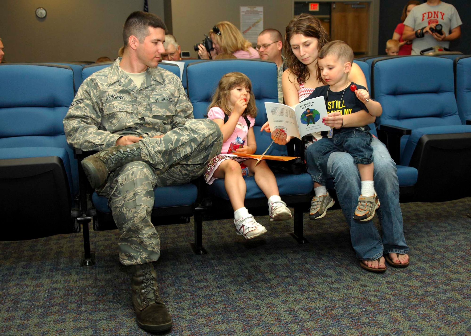 SHAW AIR FORCE BASE, S.C-- Senior Airman Sean Weygandt, 77th Fighter Squadron crew chief, looks on as his wife Rachel reads a book about parent deployments to their son, Logan and daughter, Brianna as they wait for the briefing portion of the kids deployment processing line April 24. The kids deployment line gives children of military members a chance to experience what parents go through prior to deployment. (U.S. Air Force photo/Staff Sgt. Henry Hoegen)