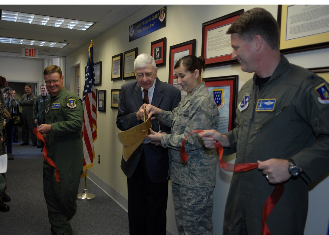 Chief Master Sgt. Anthony Manson, 316th Operations Group superintendent, Michael N. Ingrisano Jr., Airman Basic Melissa Mahan, 316 OG information management Apprentice, and Colonel Kenneth V. Volmert, 316 OG commander, cut a ribbon in the operations group command section, on April 10. Mr. Ingrisano, who was a Staff Sergeant in the 37th Troop Carrier Squadron, 316th Troop Carrier Wing (1947-1949) in the Army Air Corps, came to help unveil the wall showing the history of the 316th from World War I, World War II and The Vietnam War. (US Air Force/Amn Melissa Rodrigues)