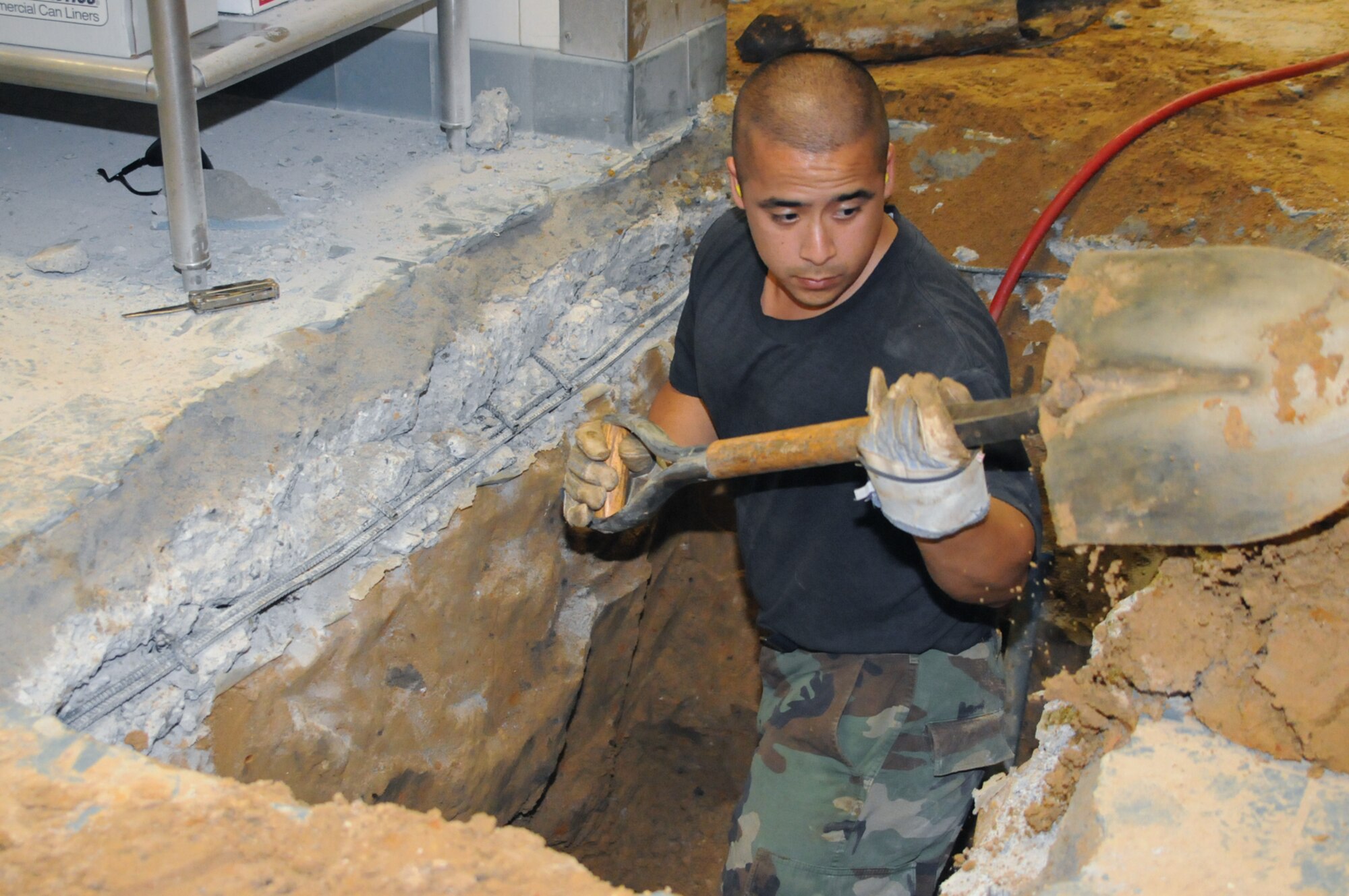 Tech. Sgt. Emmanuel Lopez, 81st Civil Engineer Squadron noncommissioned officer in charge of interior utilities, "digs deep" in trying to clear dirt and debris from around a broken sewer pipe at the Magnolia dining facility Thursday.  A blocked-up pipe caused the Magnolia to be closed this week so that vital repairs could be made by the 81st CES.  (U.S. Air Force photo by SrAmn Carlos Rodriguez)