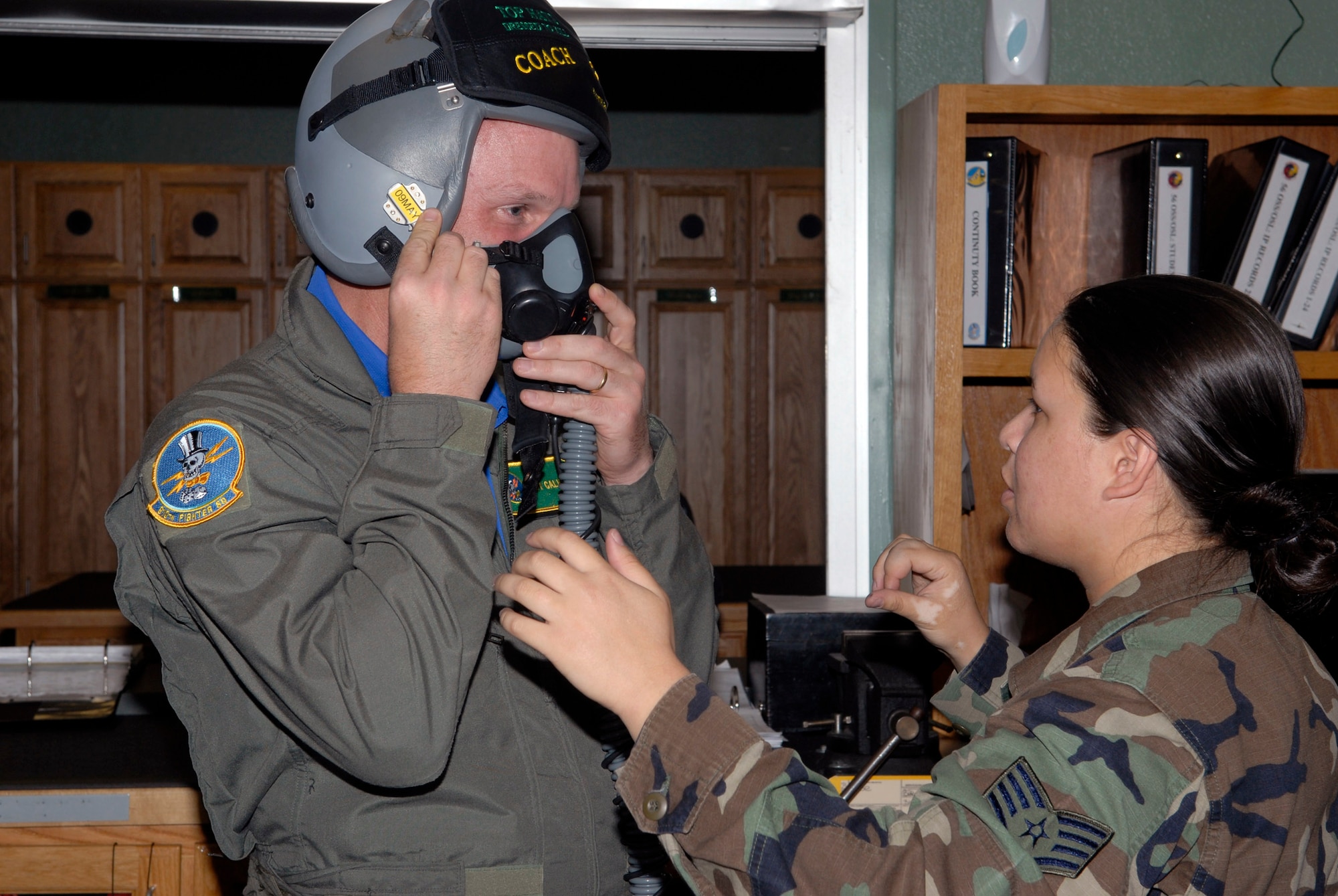 Staff Sgt. Melissa McCool assists Troy Calhoun, U.S. Air Force Academy Falcon head coach, with his face mask prior to an incentive flight April 18 with the 310th Fighter Squadron. Sergeant McCool is a 56th Operations Support Squadron aircrew flight journeyman, (U.S. Air Force photo/Staff Sgt. Steven Nabor) 
