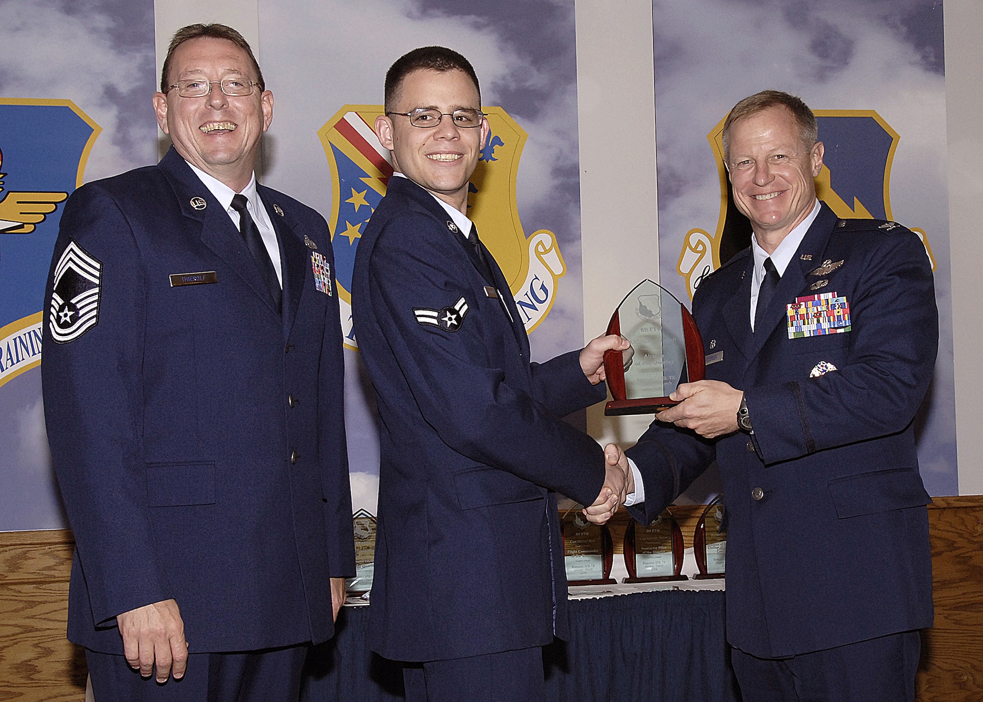 Airman 1st Class Nicholas Loerch, 80th Operations Support Squadron, accepts the Airman of the Quarter award from 80th Flying Training Wing Commander Col. David Petersen April 22 during the wing's quarterly award ceremony. Airman Loerch displayed the knowledge and skill of a veteran air traffic controller when he safely guided an aircraft experiencing radio problems to the ground. The air traffic controller was also key in safely controlling five commerical airliners diverted by recent storms. Also pictured is 80th FTW Superintendent Chief Master Sgt. Norman Theirolf. (U.S. Air Force photos/Harry Tonemah)