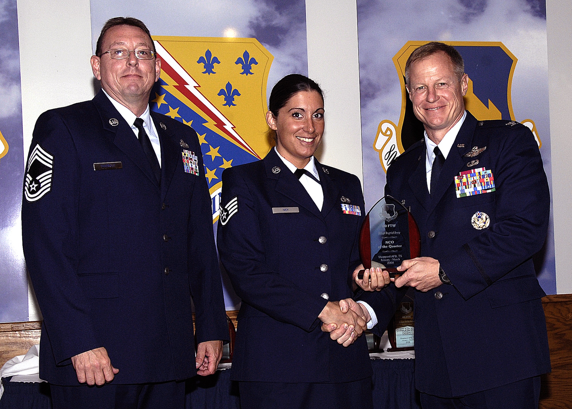 Staff Sgt. Ingrid Ivey, 80th Operations Support Squadron, accepts the NCO of the Quarter award from 80th Flying Training Wing Commander Col. David Petersen April 22 during the wing's quarterly award ceremony. Sergeant Ivey was recognized for having a 98 percent quality assurance rating on more than 400 parachutes, oxygen connectors and other flight equipment. Sergeant Ivey also led the way for other OSS personnel to provide community support to the Center for Animal Research and Education. Also pictured is 80th FTW Superintendent Chief Master Sgt. Norman Theirolf. (U.S. Air Force photos/Harry Tonemah)