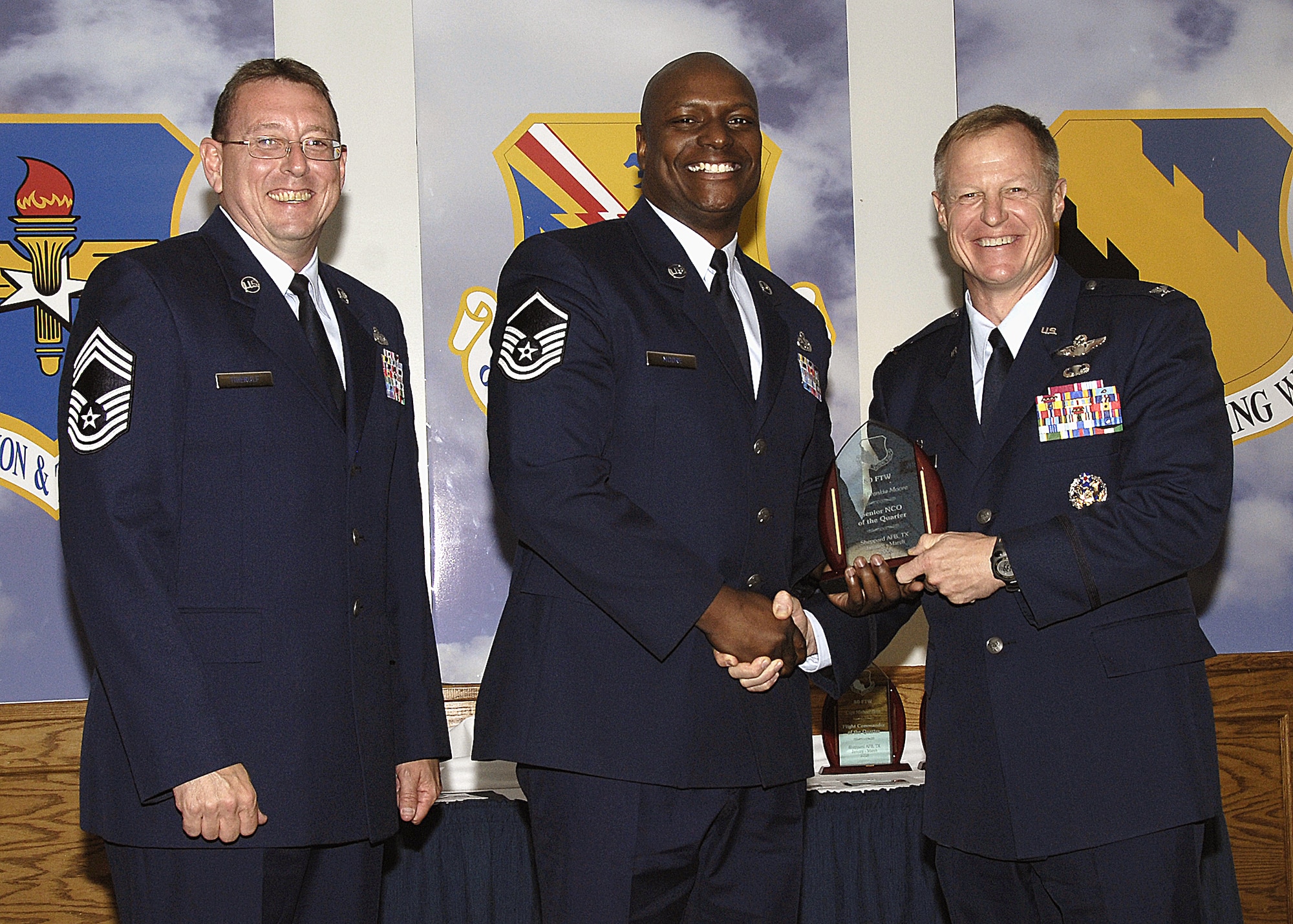 Master Sgt. Frankie Moore, 80th Flying Training Wing, accepts the Senior NCO of the Quarter award from 80th Flying Training Wing Commander Col. David Petersen April 22 during the wing's quarterly award ceremony. Sergeant Moore was recognized for managing a $248 million aircraft contract, as well as providing key support for a recent inspection. The sergeant is also active in the community, providing support as a victim advocate and collecting and distributing 38 computers to underprivileged children. Also pictured is 80th FTW Superintendent Chief Master Sgt. Norman Theirolf. (U.S. Air Force photos/Harry Tonemah)