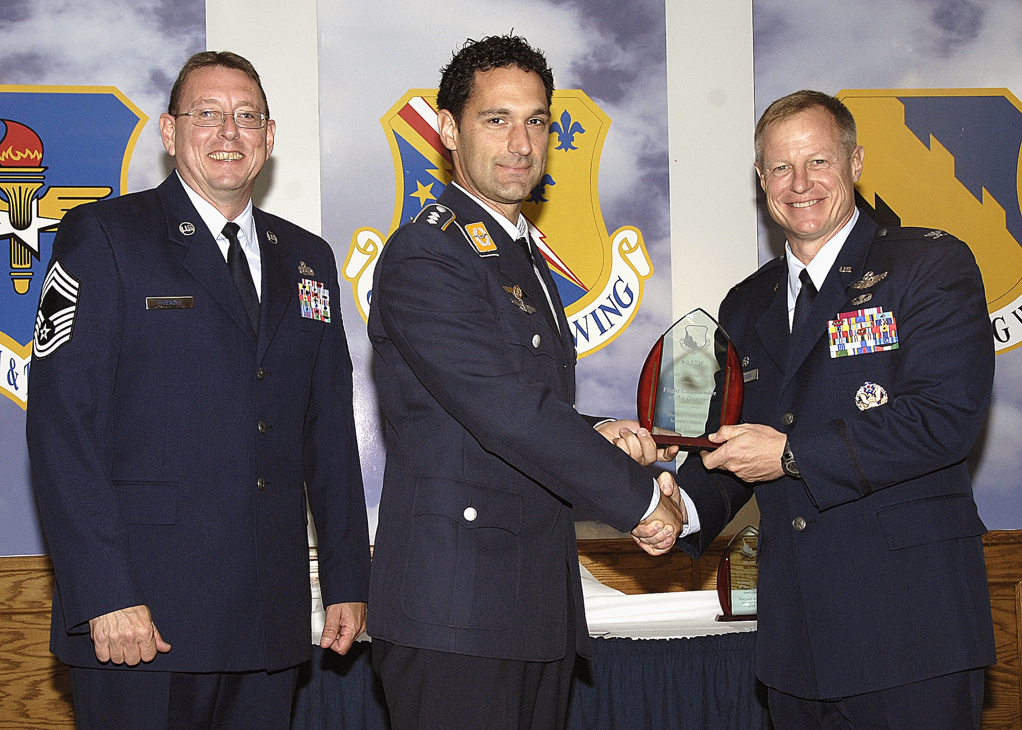 Capt. Michael Renz, 80th Operations Support Squadron, accepts the Flight Commander of the Quarter award from 80th Flying Training Wing Commander Col. David Petersen April 22 during the wing's quarterly award ceremony. Captain Renz was recognized for revamping the wing's motorcycle safety program, as well as keeping senior national representatives aware of military training responsibilities. The captain also displayed leadership by scheduling additional training missions to ensure a student pilot successfully completed the program. Also pictured is 80th FTW Superintendent Chief Master Sgt. Norman Theirolf. (U.S. Air Force photos/Harry Tonemah)