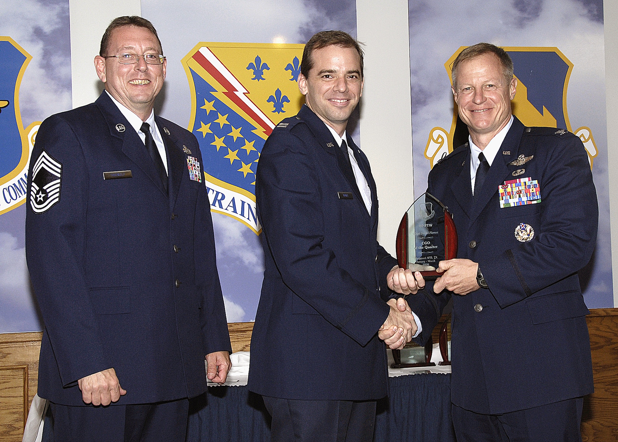 Capt. David Nance, 80th Flying Training Wing, accepts the Company Grade Officer of the Quarter award from 80th FTW Commander Col. David Petersen April 22 during the wing's quarterly award ceremony. Captain Nance was recognized for ensuring pilots' safety through the Bird Aircraft Strike Hazard program and deployment with an Introduction to Fighter Fundamentals squadron for an exercise.. He is also working on a Masters of Aerospace Science degree. Also pictured is 80th FTW Superintendent Chief Master Sgt. Norman Theirolf. (U.S. Air Force photos/Harry Tonemah)