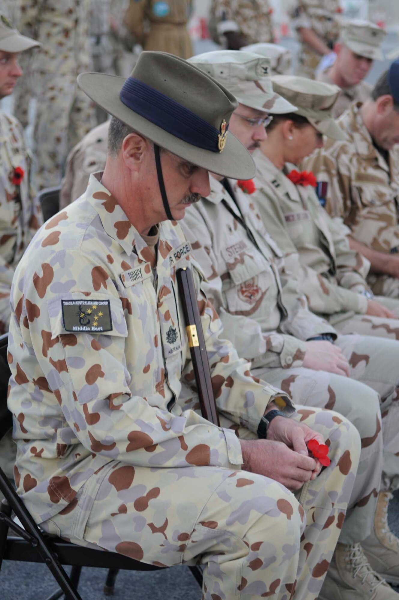 Australian Air Force, Warrant Officer Disciplinary, David Toohey, 633.4 Task Group, observes a moment of silence during the dawn service ceremony here April 25. He holds a Flanders poppy, a sign of rememberance for ANZAC day. During World War I, red poppies were seen to be among the fi rst living plants that sprouted from the devastation of the battlefi elds of northern France and Belgium. Soldiers’ folklore had it that the poppies were vivid red from having been nurtured in ground drenched with the blood of their comrades. (U.S. Air Force photo/2nd Lt. Tania Bryan)
