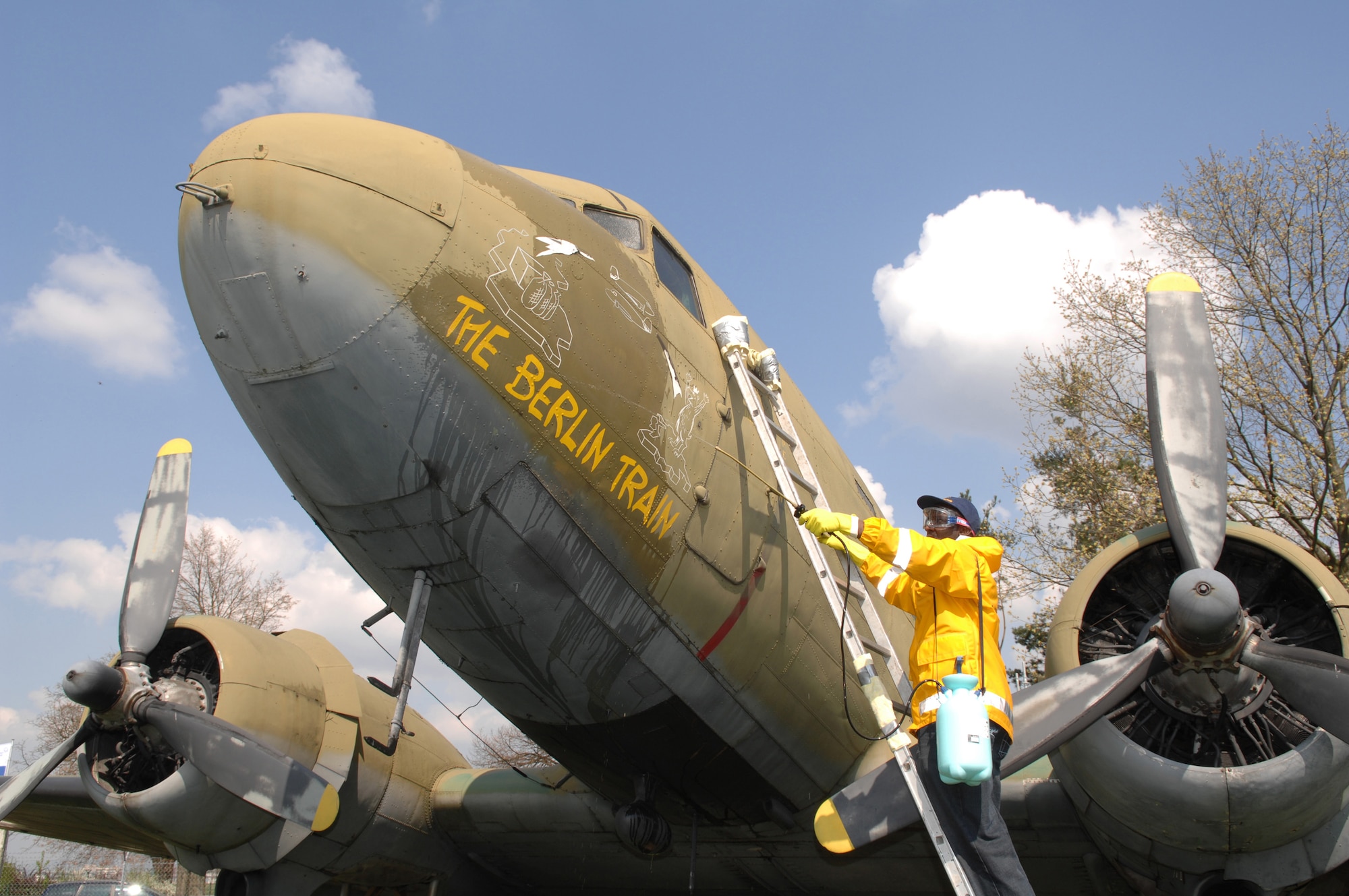 Staff Sergeant Federico Hudson cleans the nose art on a static C-54 aircraft on display at the Berlin Airlift Memorial site at the former Rhein Main Air Base near Frankfurt International Airport in Germany.  Sgt Hudson and a team of approximately 30 volunteers from Ramstein Air Base spent three days cleaning the display aircraft for refurbishing in prepartion for a Berlin Airlift 60th Anniversary Celebration to take place there in June. (U.S. Air Force photo by Tech Sergeant Corey Clements)