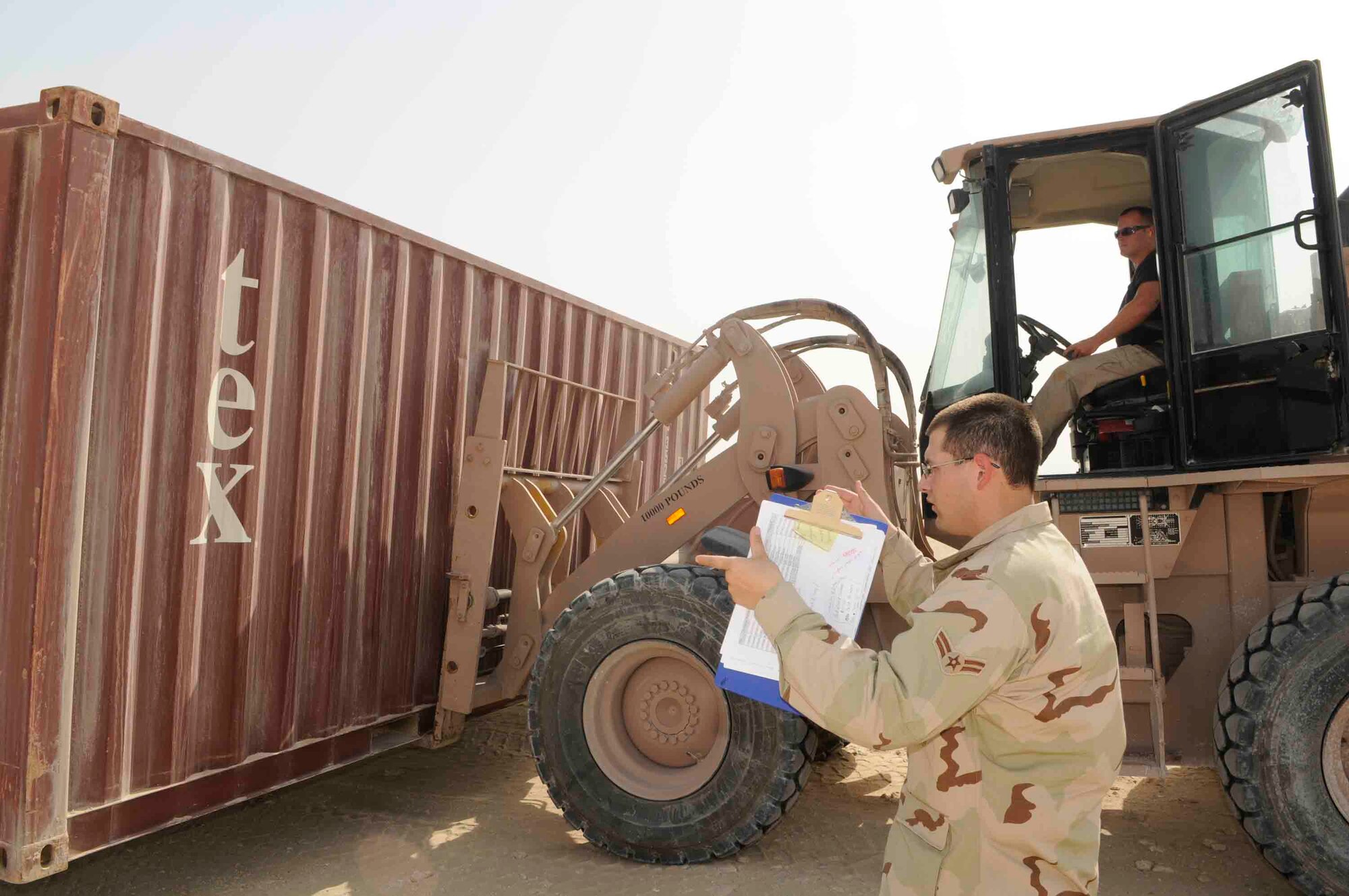 Airman 1st Class Joseph Trevino and Staff Sgt. Maurice Johnson, 379th Expeditionary Logistics Readiness Squadron, guides Chad Swift, DYNA Corporation, while he prepares to load the 3,000-pound container onto a flat bed truck at a Southwest Asia air base April 24. The 379th LRS has removed more than 500 storage containers in less than 60 days.  (U.S. Air Force photo by Tech. Sgt. Johnny Saldivar.)