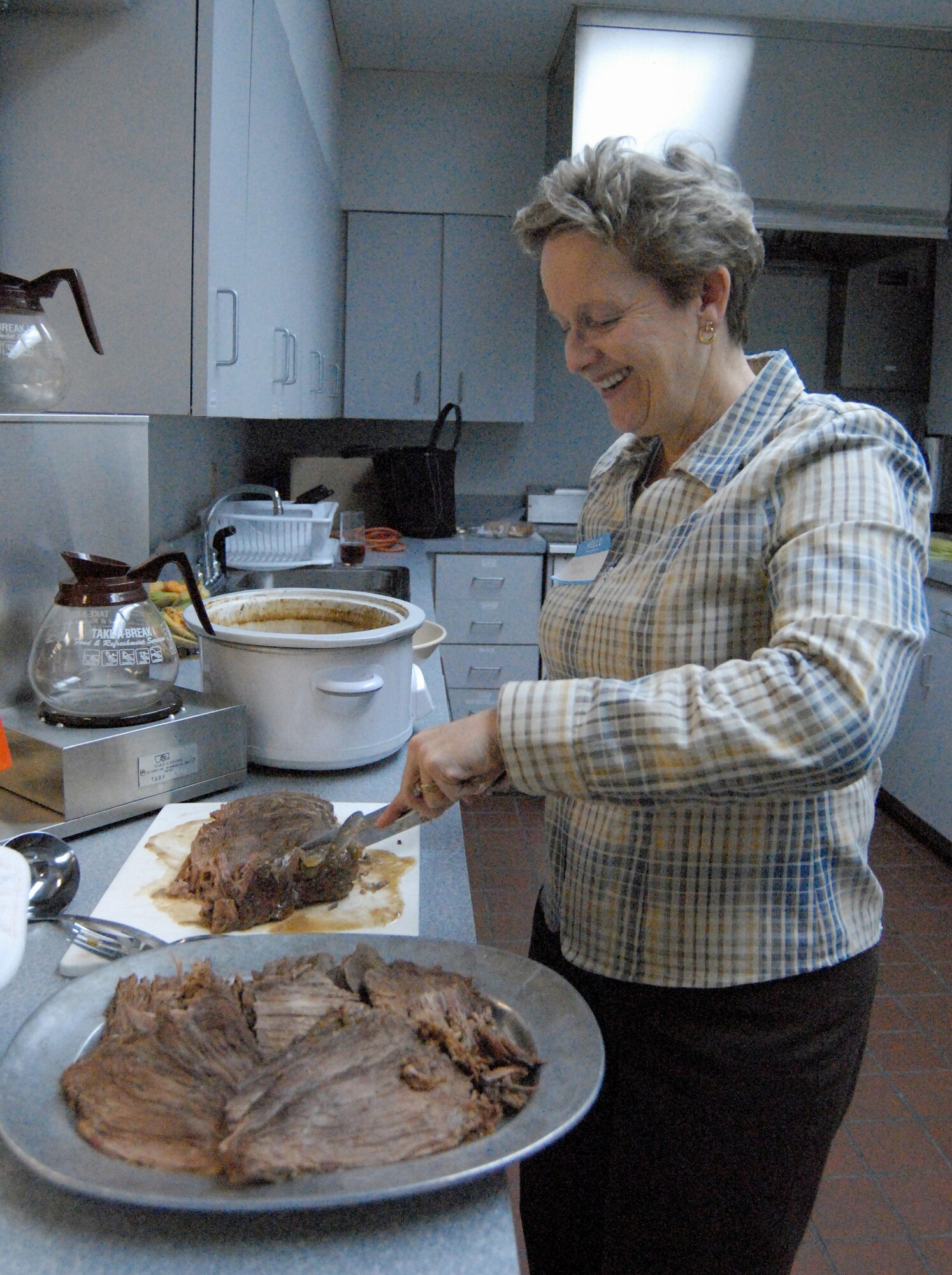 Kathie Cocklin, wife of Col. James Cocklin, 436th Aerospace Medicine Squadron commander, cuts and dishes out her famous pot roast before a Home Making 101 meeting starts. (U.S. Air Force photo/Airman 1st Class Shen-Chia Chu)