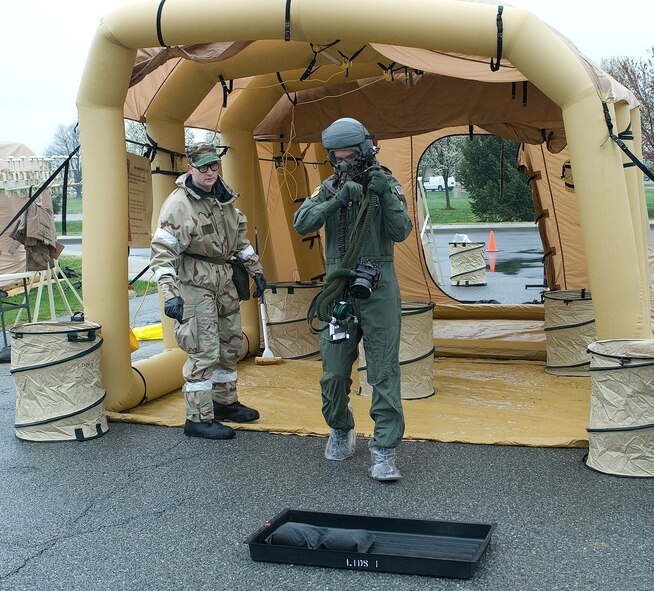 Airman 1st Class Jerry Baker, 436th Operations Support Squadron, directs aircrew member Capt. Mark Freitas, 9th Airlift Squadron, to the bootwash and on to station 2 of the aircrew decontamination line. (U.S. Air Force photo/Roland Balik)